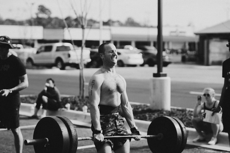 a man with no shirt is holding a barbell