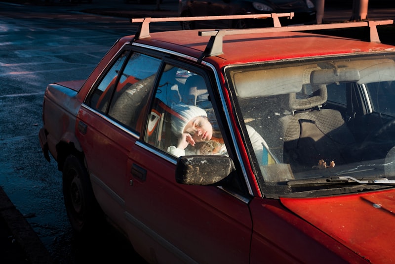 A person is resting inside a red car.