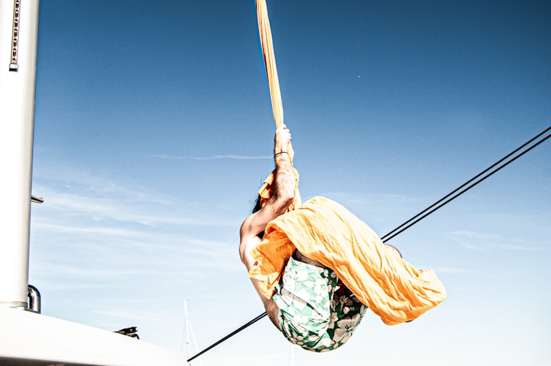 man in brown shirt and green and white plaid shorts holding brown wooden stick