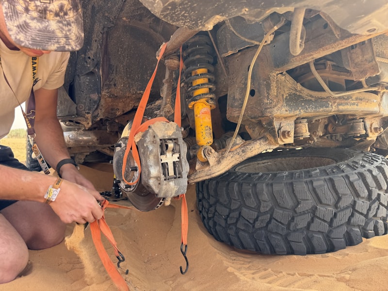 Man secures vehicle's undercarriage with straps.