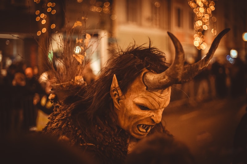 Man in krampus costume with horns and fangs.