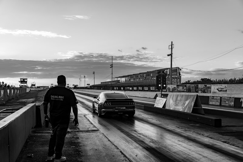 a black and white photo of a man walking towards a car