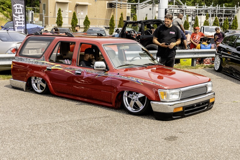 Red customized suv with lowered suspension at a car show.