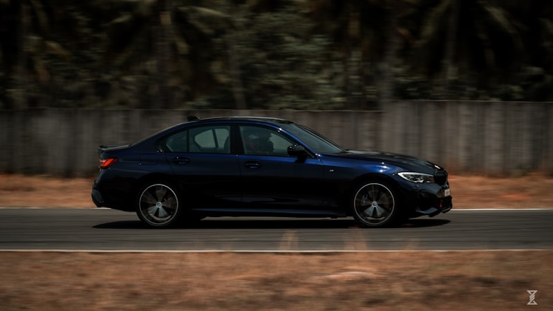 A dark blue sedan driving on a track.