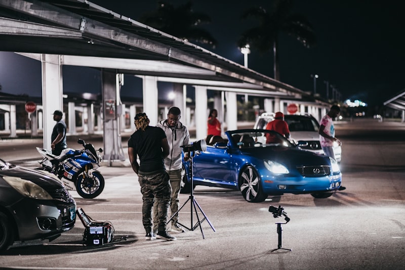 man in black jacket standing beside blue car