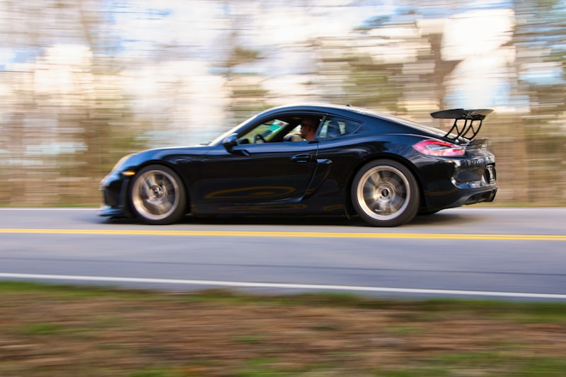 A black sports car speeds down a road.