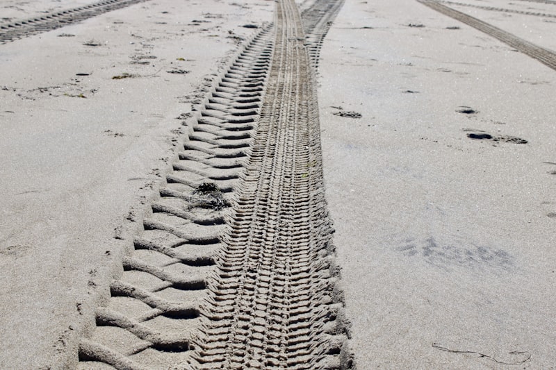 Tire tracks imprinted in the sand on a beach.