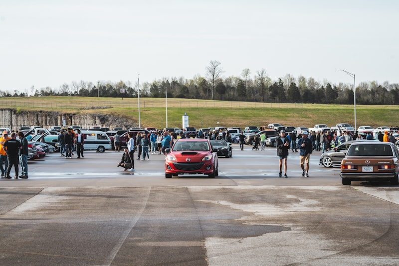 a group of people standing around a car in a parking lot