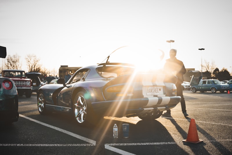 man in brown jacket standing beside black car
