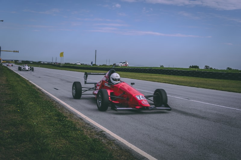 A red race car speeds down the track.
