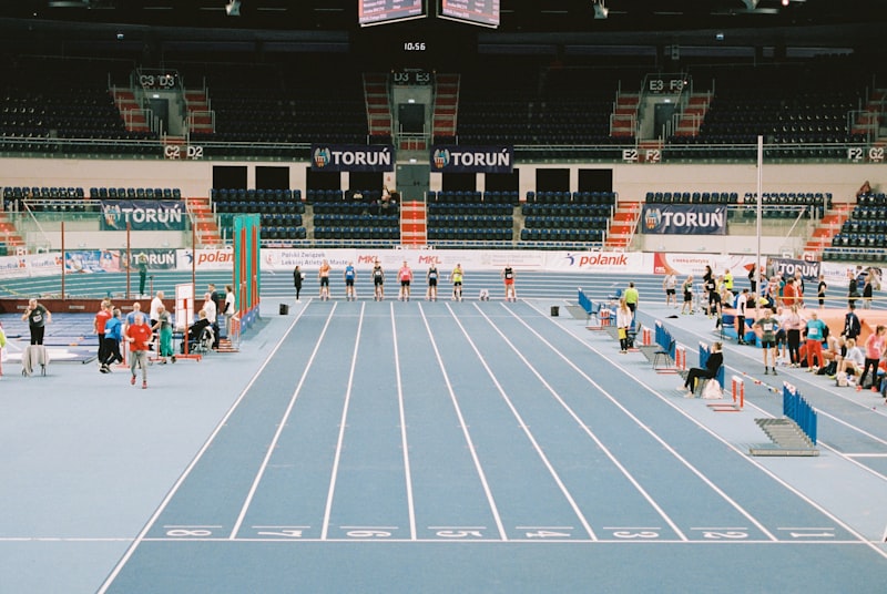 Track athletes prepare to race in an indoor stadium.