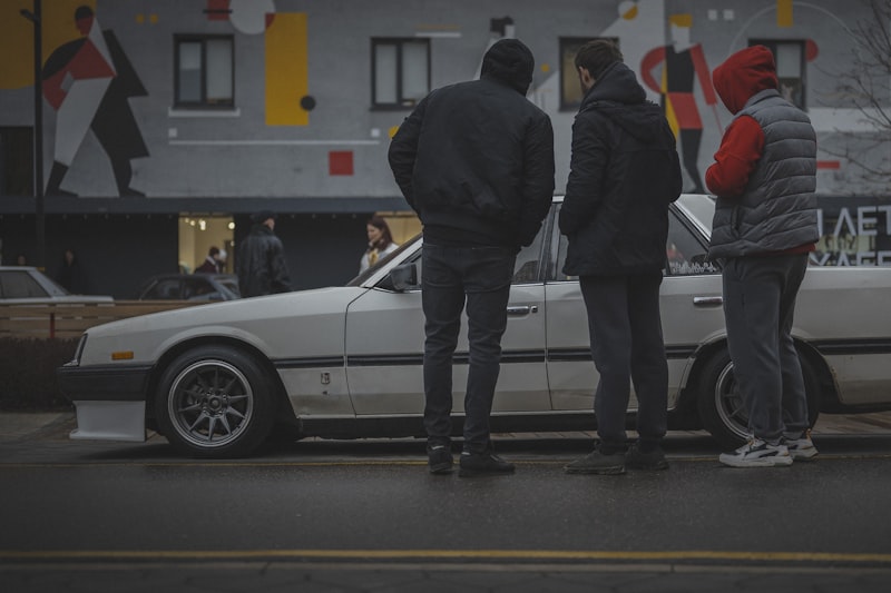 Three people stand by a white vintage car.