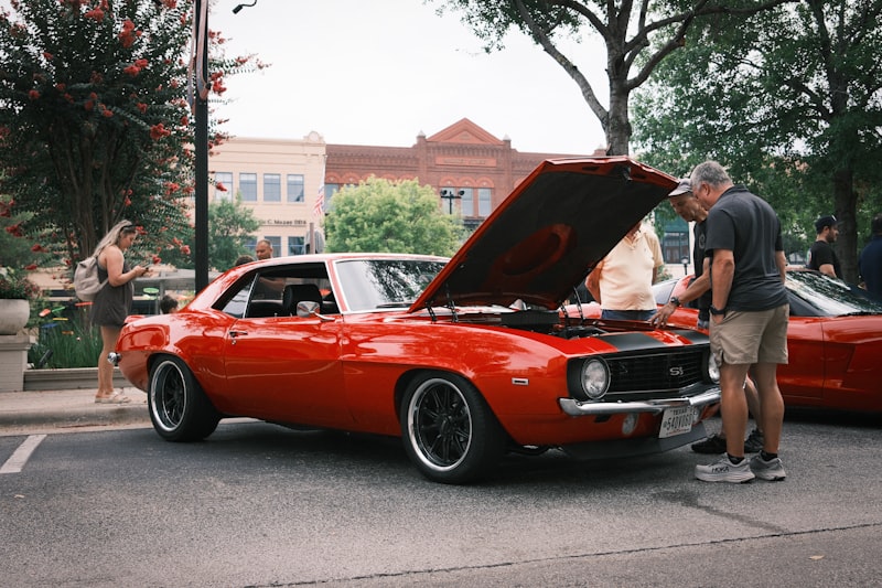 A man standing next to a red car with its hood open