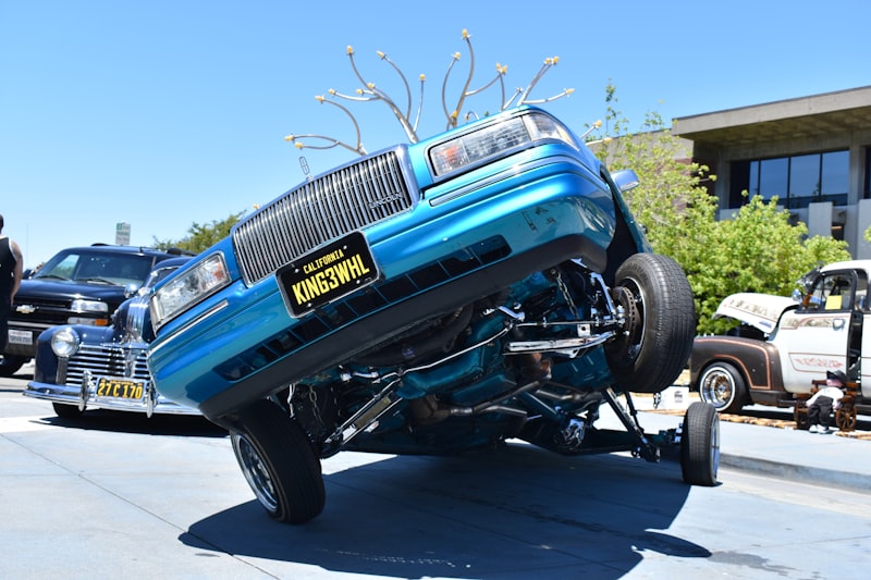 Turquoise lowrider car performing a hydraulic lift