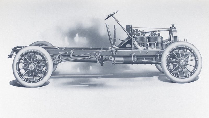 Antique automobile chassis with engine and wheels.