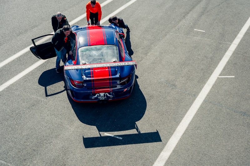 Mechanics surround a race car on the track.