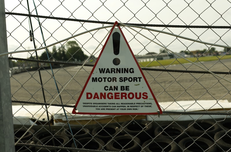 Warning sign about dangerous motor sport on fence